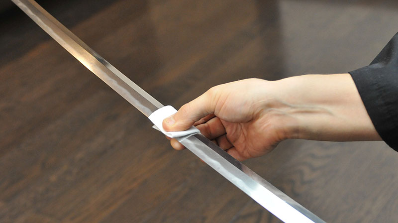 Applying the sword oil on Japanese sword blade with paper