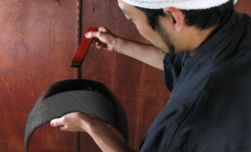 A craftsmen applying urushi lacquer to a dodai with a brush.