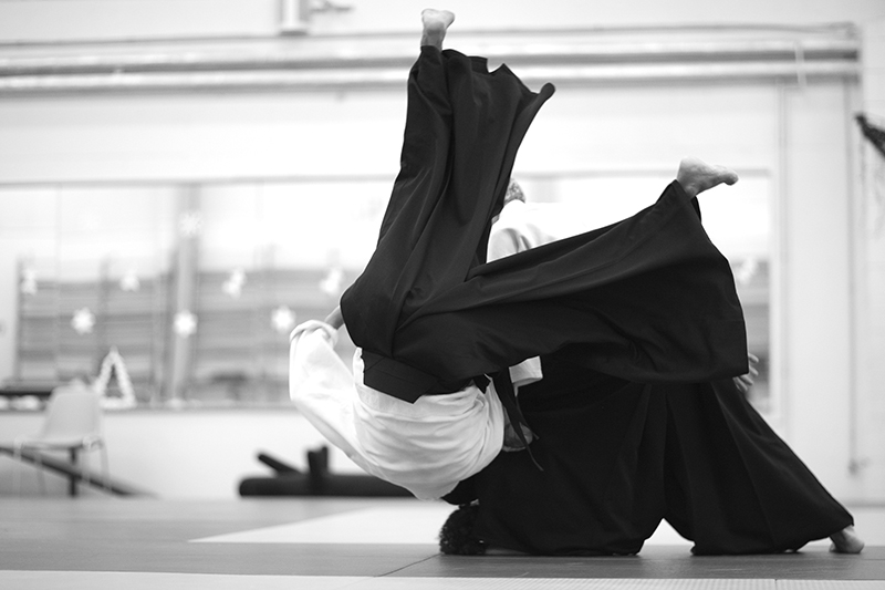 An uke is thrown by an aikidoka's forceful technique.