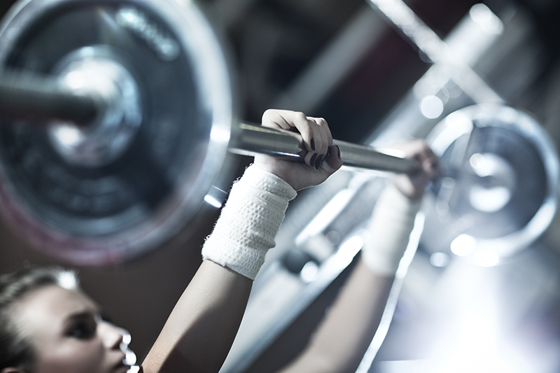 Young woman weight training. Focus on hand.